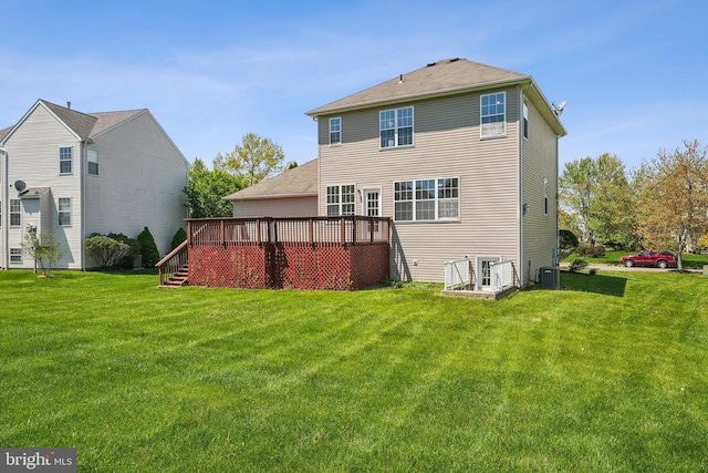 rear view of property featuring a lawn, a wooden deck, and central AC unit