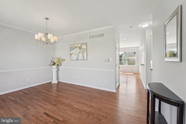 unfurnished dining area featuring ornamental molding, a chandelier, wood finished floors, and visible vents