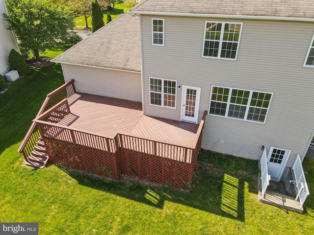 rear view of property featuring a lawn, a shingled roof, and a deck