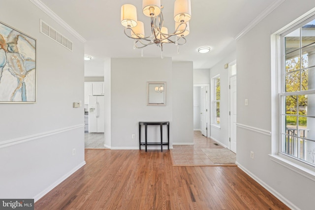 entrance foyer with an inviting chandelier, baseboards, wood finished floors, and visible vents