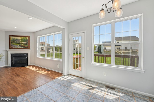 doorway featuring a chandelier, baseboards, visible vents, and a fireplace