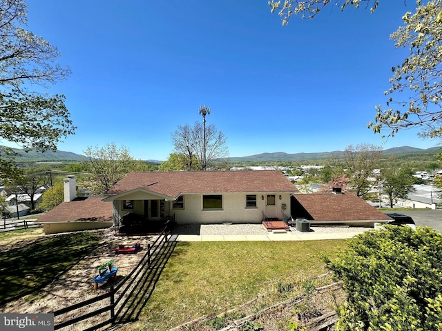 back of property featuring a yard, fence, a mountain view, and a patio area