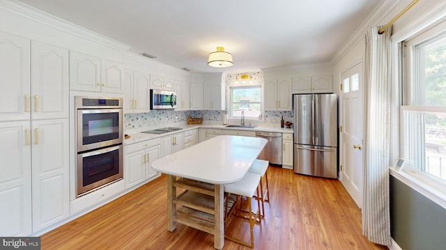 kitchen with light wood-type flooring, a sink, backsplash, and stainless steel appliances