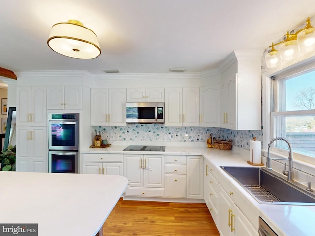kitchen with a sink, appliances with stainless steel finishes, white cabinets, and light countertops