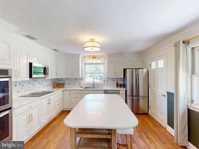 kitchen with a sink, appliances with stainless steel finishes, decorative backsplash, and light wood-type flooring