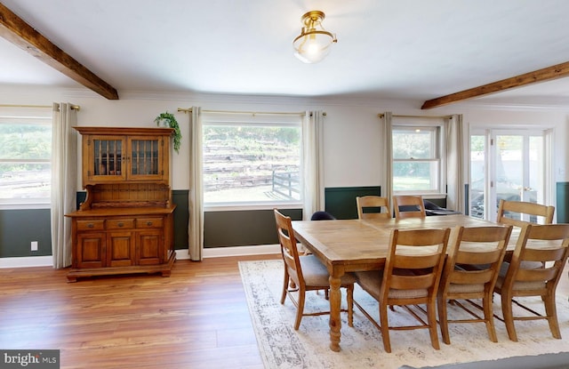 dining room with baseboards, beam ceiling, and light wood-style floors
