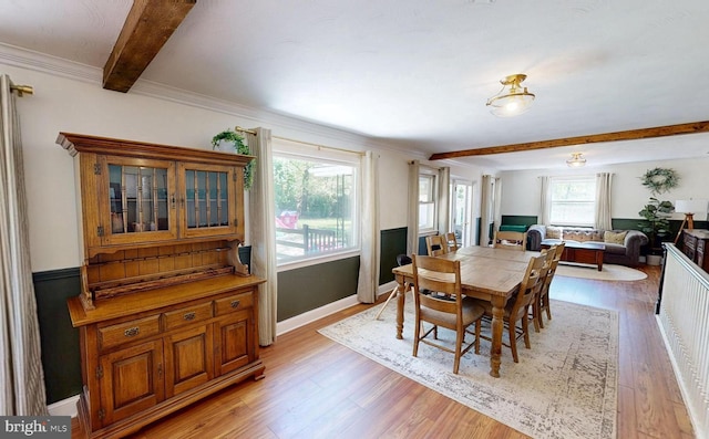 dining space with a healthy amount of sunlight, light wood-type flooring, and beam ceiling