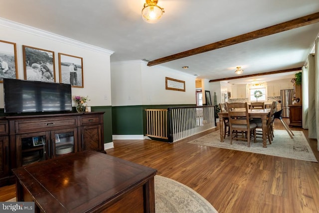 living area with ornamental molding, beam ceiling, wainscoting, and wood finished floors