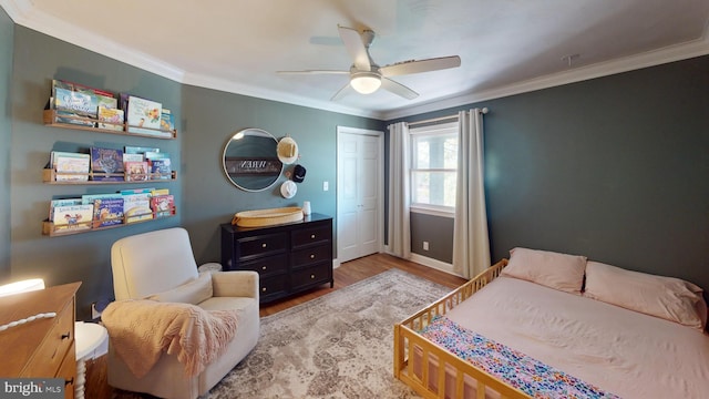bedroom featuring crown molding, ceiling fan, baseboards, wood finished floors, and a closet