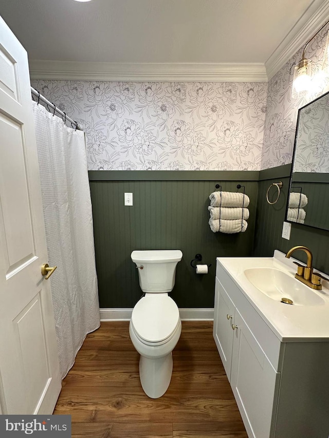 bathroom featuring wainscoting, wood finished floors, vanity, toilet, and ornamental molding