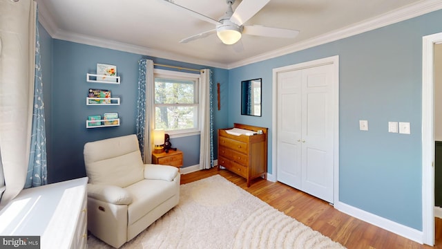 sitting room with a ceiling fan, baseboards, ornamental molding, and wood finished floors