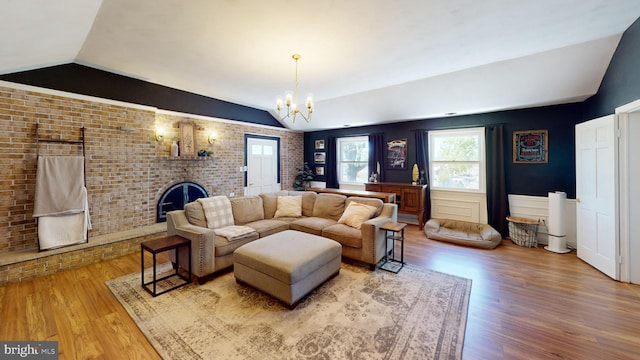 living area with wood finished floors, brick wall, and lofted ceiling