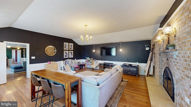 living area featuring an accent wall, lofted ceiling, light wood finished floors, and a fireplace