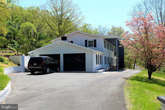 view of front of property with a garage, aphalt driveway, and brick siding