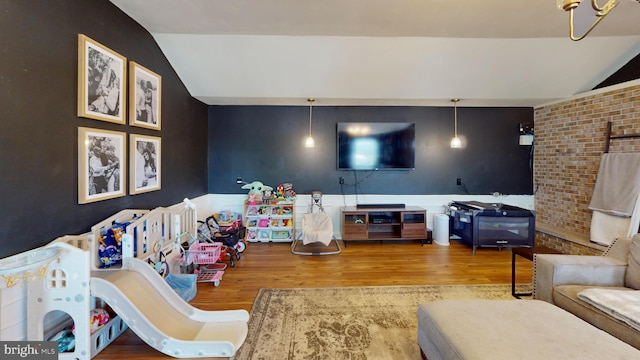 living area featuring brick wall, wood finished floors, and lofted ceiling