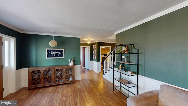 corridor with ornamental molding, wainscoting, stairs, and wood finished floors