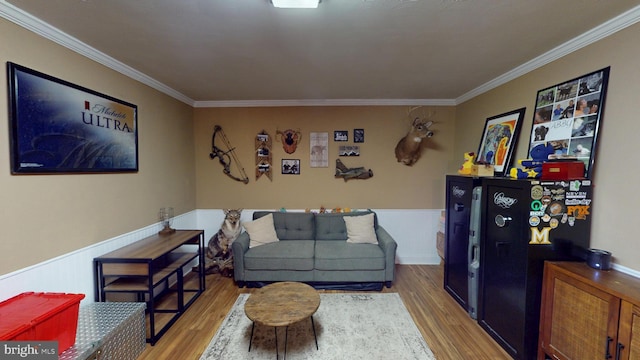 living area featuring ornamental molding, wood finished floors, and a wainscoted wall
