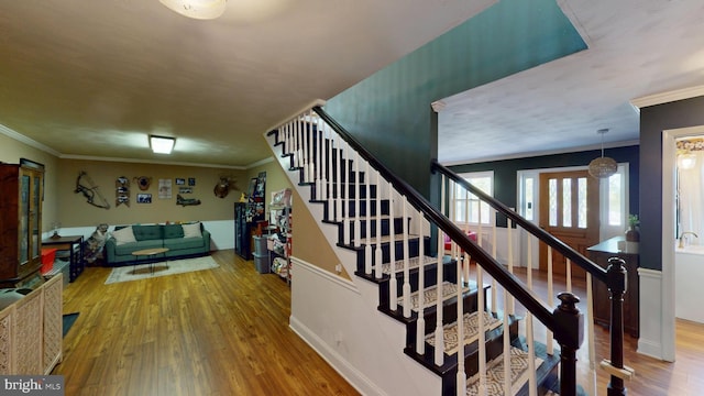 stairs featuring ornamental molding and wood finished floors