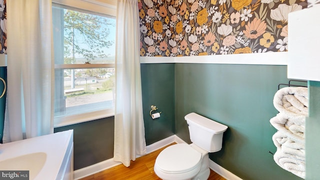 bathroom with baseboards, wood finished floors, and toilet