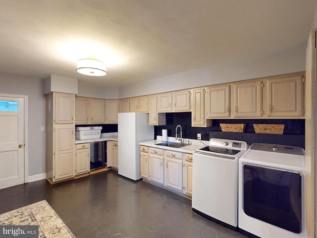 kitchen with washer and dryer, a sink, light countertops, freestanding refrigerator, and baseboards