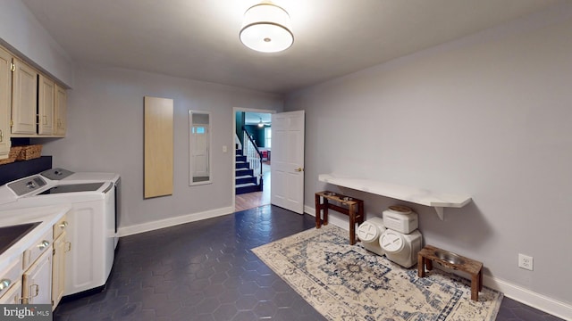 washroom with baseboards, cabinet space, and washing machine and clothes dryer