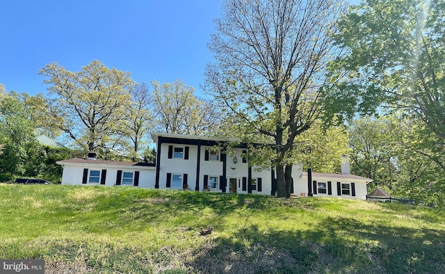 view of front facade with a chimney and a front lawn