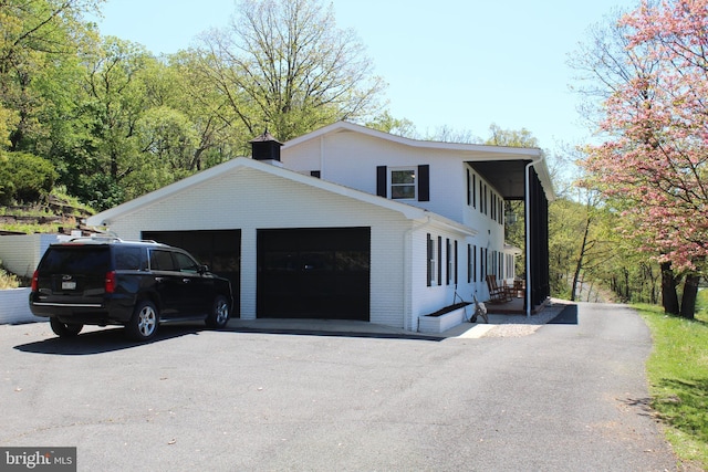 view of home's exterior featuring brick siding, aphalt driveway, and a chimney