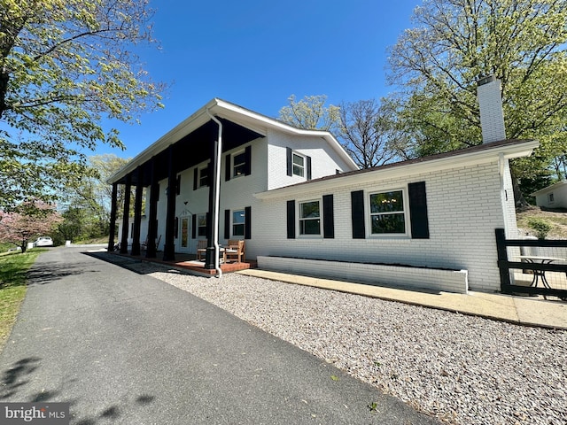view of front of property featuring brick siding and a chimney