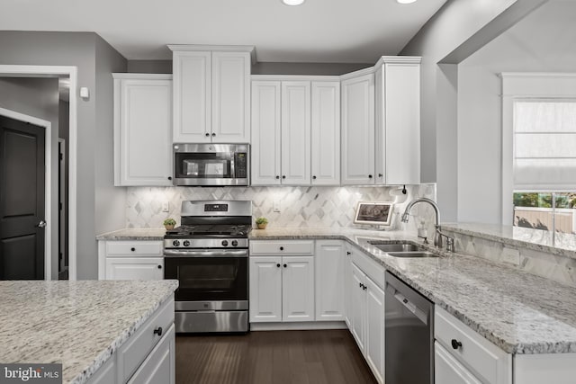 kitchen with a sink, white cabinetry, backsplash, and stainless steel appliances