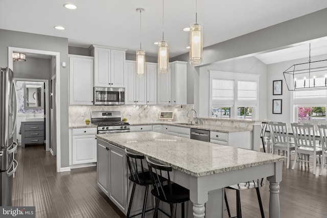 kitchen featuring backsplash, stainless steel appliances, a breakfast bar area, and a peninsula