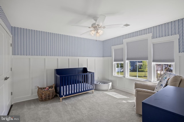 bedroom with carpet flooring, a decorative wall, and wallpapered walls