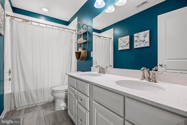 bathroom with a sink, toilet, double vanity, and visible vents