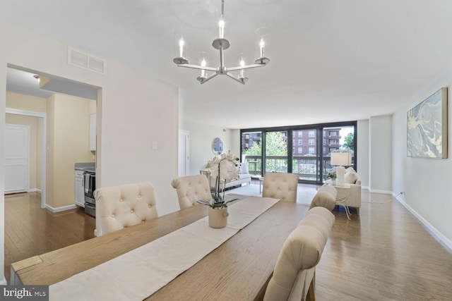 dining room with a wall of windows, visible vents, wood finished floors, baseboards, and a chandelier