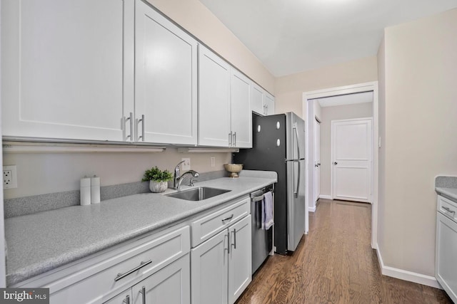 kitchen featuring dark wood finished floors, a sink, light countertops, stainless steel appliances, and white cabinetry