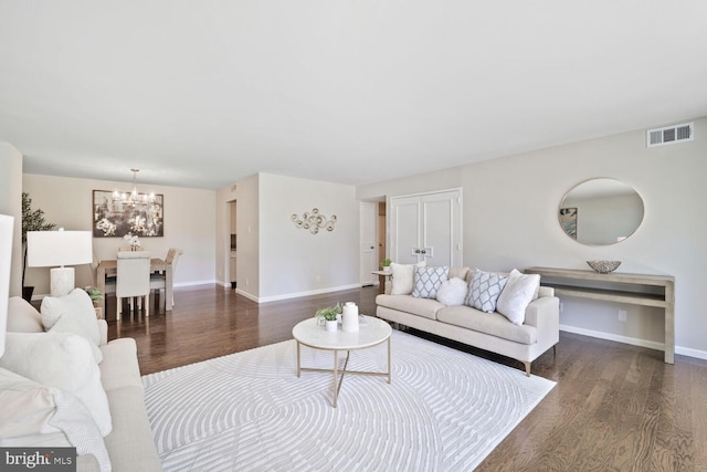 living room with baseboards, visible vents, dark wood-style floors, and a notable chandelier