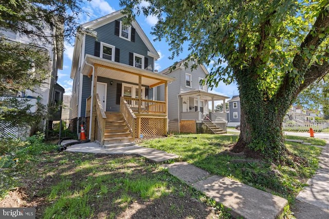 american foursquare style home with a front yard, covered porch, and stairway
