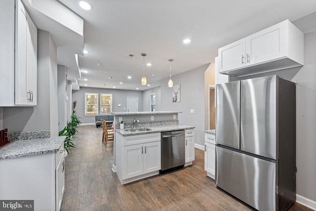 kitchen with dark wood-style flooring, a sink, stainless steel appliances, open floor plan, and white cabinetry