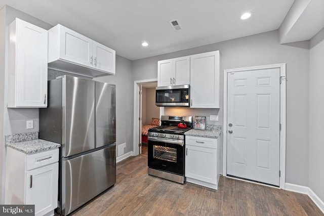 kitchen with white cabinets, stainless steel appliances, baseboards, and dark wood-style flooring