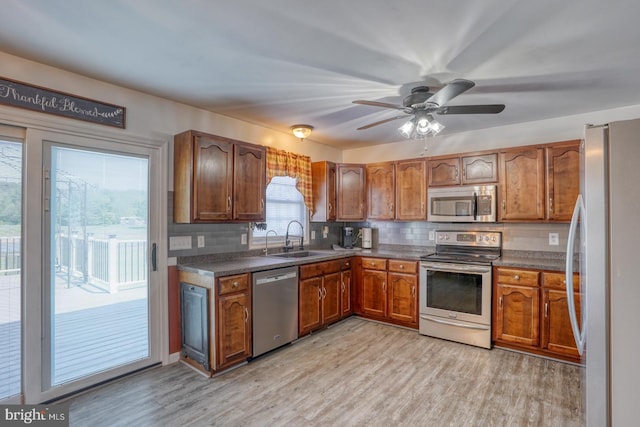 kitchen featuring a sink, appliances with stainless steel finishes, backsplash, and light wood-type flooring