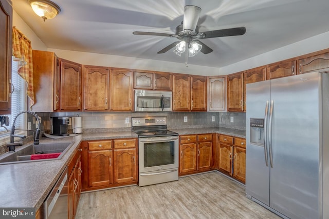 kitchen featuring stainless steel appliances, brown cabinetry, a sink, and light wood finished floors