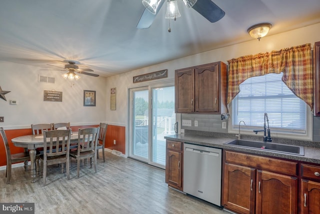 kitchen with a ceiling fan, dark countertops, dishwasher, a sink, and light wood finished floors