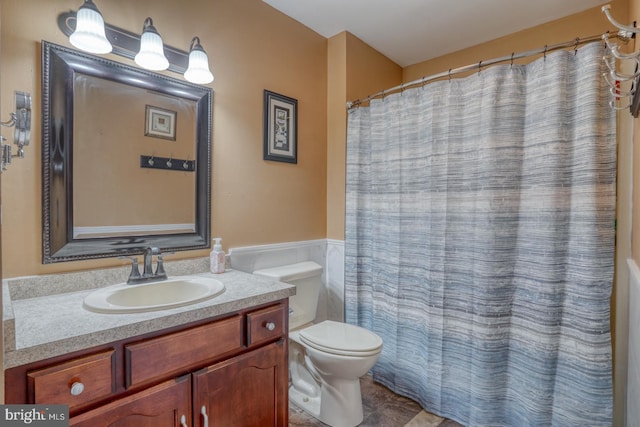 bathroom featuring vanity, wainscoting, toilet, and curtained shower