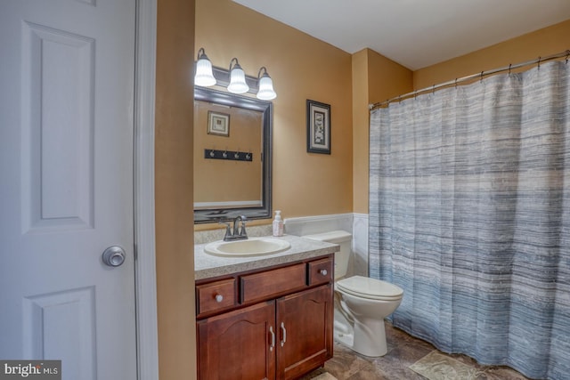 bathroom featuring vanity, wainscoting, and toilet