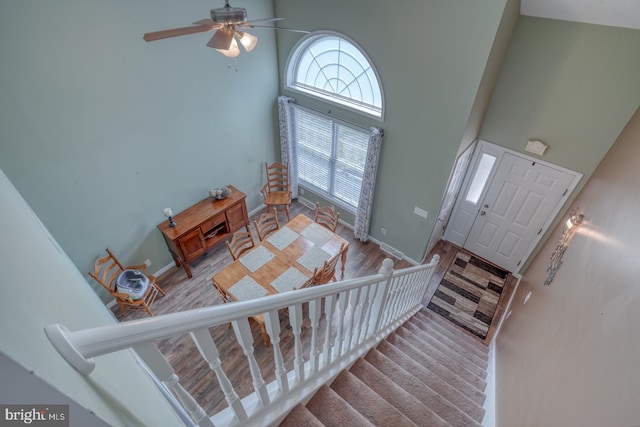 entryway with a high ceiling, ceiling fan, plenty of natural light, and wood finished floors