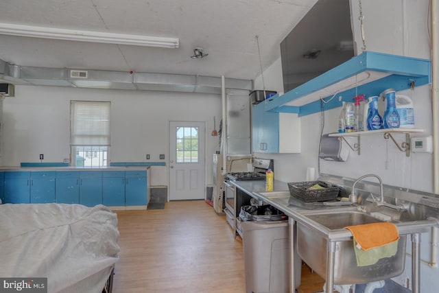 kitchen featuring visible vents, open shelves, stainless steel gas range, light wood-type flooring, and blue cabinetry