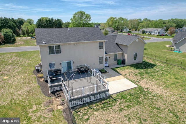 rear view of house featuring fence, a wooden deck, roof with shingles, central AC unit, and a yard