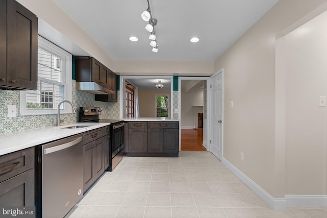 kitchen with a sink, tasteful backsplash, light countertops, and appliances with stainless steel finishes