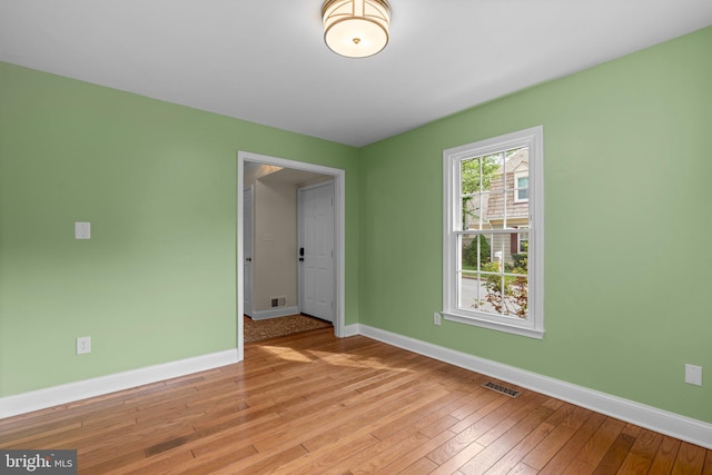 spare room featuring light wood-style floors, visible vents, and baseboards