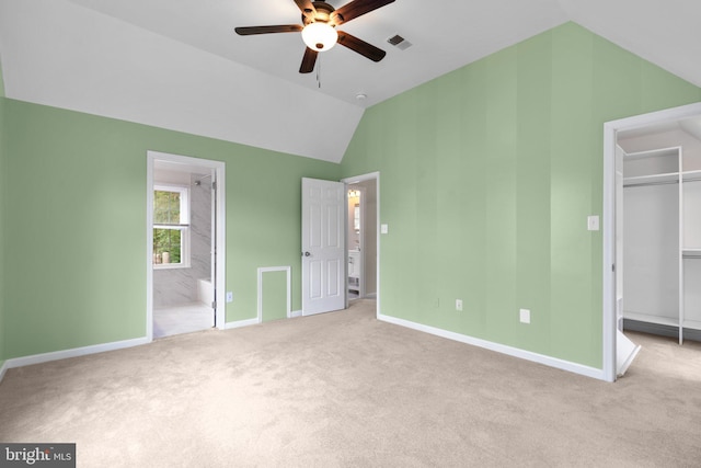 unfurnished bedroom featuring a walk in closet, visible vents, lofted ceiling, and carpet floors