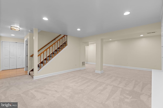 finished basement featuring light colored carpet, stairs, visible vents, and recessed lighting